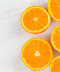 Fresh sliced oranges on white wooden surface, vibrant citrus fruit